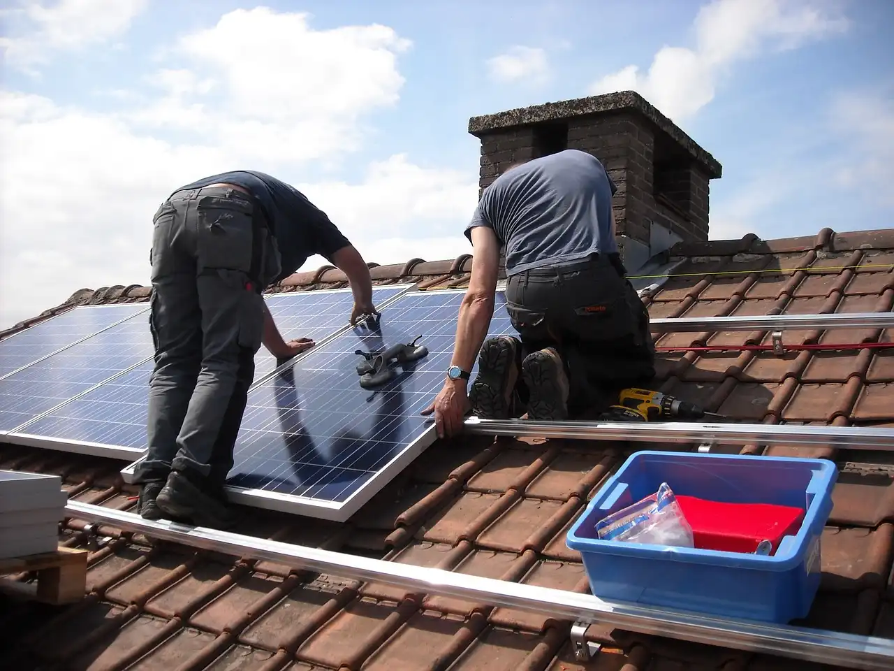 Two men installing solar panels on a roof